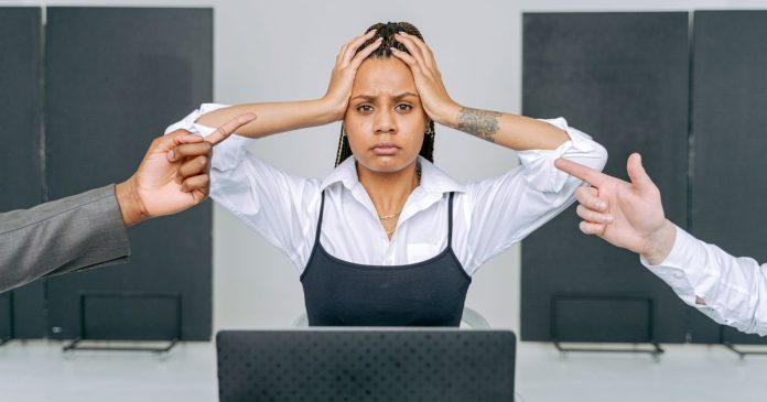 Stressed woman at a laptop during a tense workplace interaction